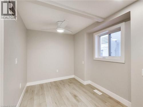 Room featuring light wood-finish flooring, a modern ceiling fan with integrated lighting, a recessed window, and neutral-toned walls with white trim - 229 Parkdale Avenue N, Hamilton, ON 