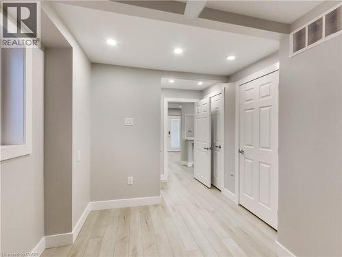 Hallway featuring light wood-finish flooring, recessed lighting, white baseboards, and multiple paneled doors - 229 Parkdale Avenue N, Hamilton, ON 