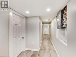 Finished lower-level hallway featuring recessed lighting, a paneled interior door, and light-toned tile flooring - 