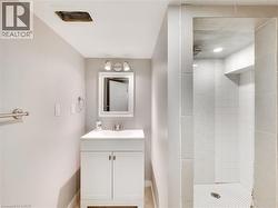 Bathroom featuring a white vanity with integrated sink, chrome faucet, and rectangular mirror with task lighting - 