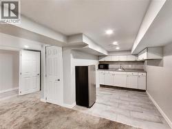 Lower-level kitchenette featuring white cabinetry, a stainless steel refrigerator, and a tile backsplash - 