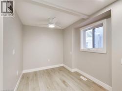 Room featuring light wood-finish flooring, a modern ceiling fan with integrated lighting, a recessed window, and neutral-toned walls with white trim - 