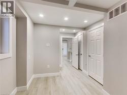 Hallway featuring light wood-finish flooring, recessed lighting, white baseboards, and multiple paneled doors - 