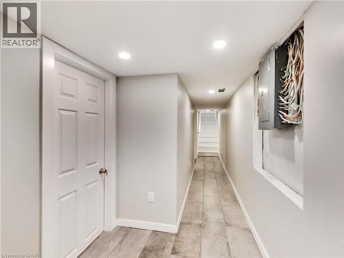 Finished lower-level hallway featuring recessed lighting, a paneled interior door, and light-toned tile flooring - 229 Parkdale Avenue N, Hamilton, ON 