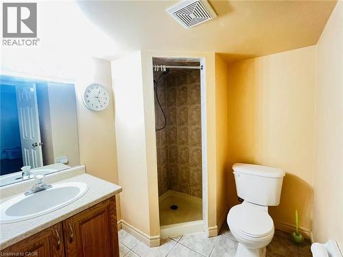 Bathroom featuring a stand-up shower with tiled walls, a vanity with wood-finish cabinetry, a white basin sink, and a toilet - 136 Hidden Creek Drive, Kitchener, ON 