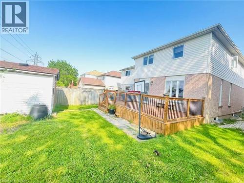 Expansive rear yard featuring a large wood deck with black metal balusters, green lawn, and a separate storage shed - 136 Hidden Creek Drive, Kitchener, ON 