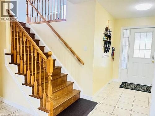 Entryway featuring a wood staircase with turned balusters, a wood handrail, and a white paneled door with frosted glass inserts - 136 Hidden Creek Drive, Kitchener, ON 
