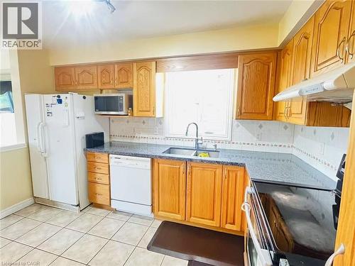 Kitchen featuring wood cabinetry, light-toned tile flooring, and a window above the sink - 136 Hidden Creek Drive, Kitchener, ON 