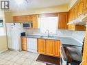 Kitchen featuring wood cabinetry, light-toned tile flooring, and a window above the sink - 136 Hidden Creek Drive, Kitchener, ON 