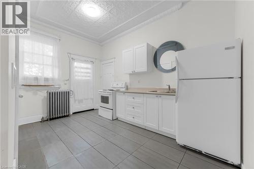 Kitchen featuring white cabinetry, neutral countertops, and gray tile flooring - 1371 Main Street E, Hamilton, ON - Indoor Photo Showing Kitchen
