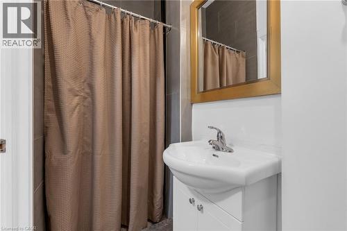 Bathroom featuring a white vanity with integrated sink, chrome faucet, and a gold-framed mirror - 1371 Main Street E, Hamilton, ON - Indoor Photo Showing Bathroom