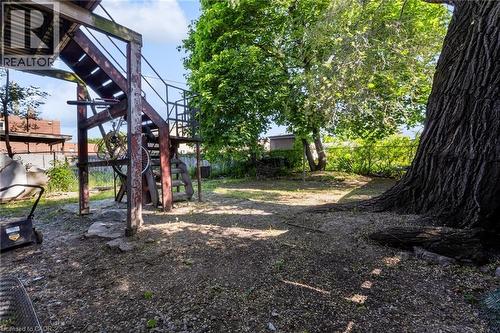 Spacious outdoor area featuring mature trees and a multi-level deck structure with stairs and metal railings - 1371 Main Street E, Hamilton, ON - Outdoor