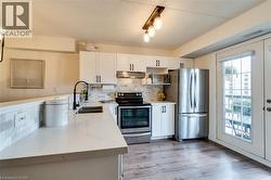 Open-concept living space featuring wood-finish flooring, a contemporary chandelier, and a partial wall separating the kitchen - 