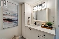 Bathroom featuring a white vanity with a rectangular undermount sink, a stone-finish countertop, and matte black fixtures - 