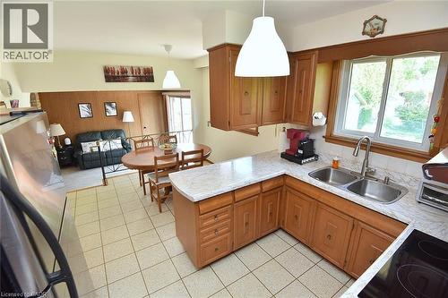 Kitchen featuring wood cabinetry, white countertop surfaces, and a double basin stainless steel sink with a gooseneck faucet - 372 Fennell Avenue W, Hamilton, ON 