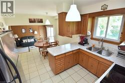 Kitchen featuring wood cabinetry, white countertop surfaces, and a double basin stainless steel sink with a gooseneck faucet - 