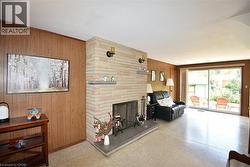 Stone fireplace with a hearth, wood paneling, and sliding glass doors to the exterior - 