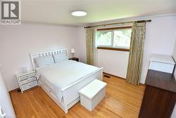 Hardwood flooring throughout featuring a window with natural wood trim, crown molding, and a flush mount ceiling light - 