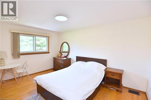 Hardwood flooring throughout, featuring a broad window with a natural wood frame, a flush-mount ceiling light fixture, and light-toned wall finishes - 372 Fennell Avenue W, Hamilton, ON 