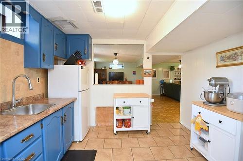 Kitchen featuring blue cabinetry, a stainless steel sink, and a tan countertop - 372 Fennell Avenue W, Hamilton, ON 