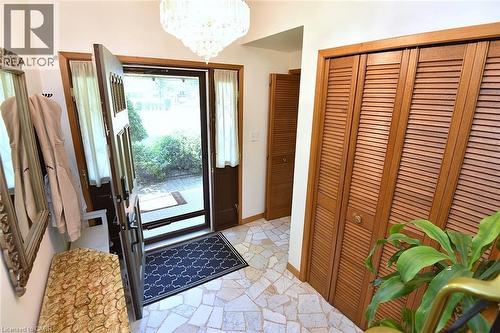 Foyer featuring irregular-shaped tile flooring, a decorative chandelier, and louvered bifold doors - 372 Fennell Avenue W, Hamilton, ON 