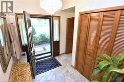 Foyer featuring irregular-shaped tile flooring, a decorative chandelier, and louvered bifold doors - 