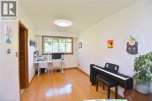 Spacious room featuring wood-finish flooring, a large window, crown molding, a flush-mount ceiling light, and a louvered door - 372 Fennell Avenue W, Hamilton, ON 