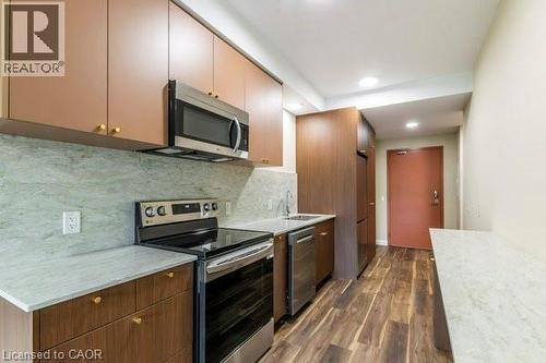 Kitchen featuring stainless steel appliances, dark wood finished floors, decorative backsplash, and recessed lighting - 580 Coldstream Drive Unit# 307, Waterloo, ON 