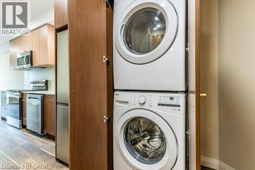 Laundry area with stacked washing machine and dryer and light wood-style flooring - 580 Coldstream Drive Unit# 307, Waterloo, ON 