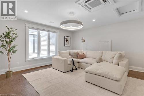 Spacious room featuring wood-finish flooring, recessed lighting, and a large window with white louvered blinds - 12 George Street, Waterloo, ON 