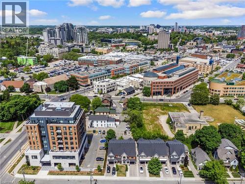 Modern mixed-use urban development featuring a contemporary high-rise building with balconies, adjacent to a row of townhouses with private driveways - 12 George Street, Waterloo, ON 