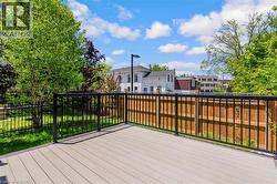 Outdoor composite decking with black metal railings, bordered by a wooden privacy fence and a wrought iron fence - 