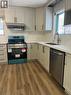 Modern kitchen featuring light-toned cabinetry with dark hardware, wood-finish flooring, stainless steel appliances, a double basin sink with a high-arc faucet, and white countertops - 102 Massey Avenue, Kitchener, ON 