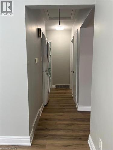 Hallway featuring wood-finish flooring, white baseboards, and light gray walls - 102 Massey Avenue, Kitchener, ON 