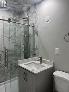 Bathroom featuring a walk-in shower with clear glass enclosure, marble-patterned wall tiles, and a rainfall shower head - 