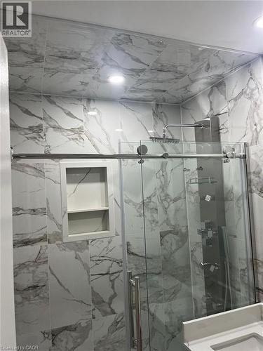 Shower enclosure featuring full-height marble-look tile, a built-in shower niche, and a rain shower head with a multi-function panel - 102 Massey Avenue, Kitchener, ON 