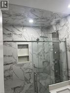 Shower enclosure featuring full-height marble-look tile, a built-in shower niche, and a rain shower head with a multi-function panel - 