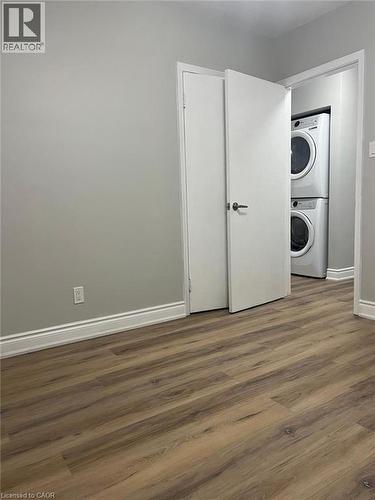 Dedicated laundry closet featuring a stacked white washer and dryer unit - 102 Massey Avenue, Kitchener, ON 
