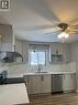Kitchen featuring light gray cabinetry, white countertops, stainless steel appliances, a double basin sink with a gooseneck faucet, and wood-finish flooring - 102 Massey Avenue, Kitchener, ON 