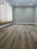 Spacious room featuring wood-finish flooring, light gray wall paint, and recessed ceiling lighting - 