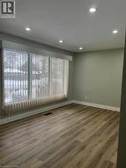 Spacious room featuring wood-finish flooring, recessed ceiling lighting, and a large window with vertical blinds - 
