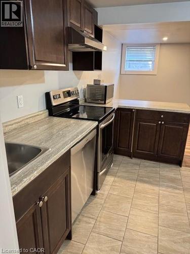 Kitchen featuring dark wood cabinetry, light-toned countertops, stainless steel appliances, and tiled flooring - 113 Cornerbrook Crescent Unit# 2, Waterloo, ON 
