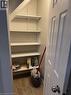 Under-stair storage closet featuring adjustable shelving, wood-finish flooring, and a paneled door with a brushed nickel knob - 113 Cornerbrook Crescent Unit# 2, Waterloo, ON 