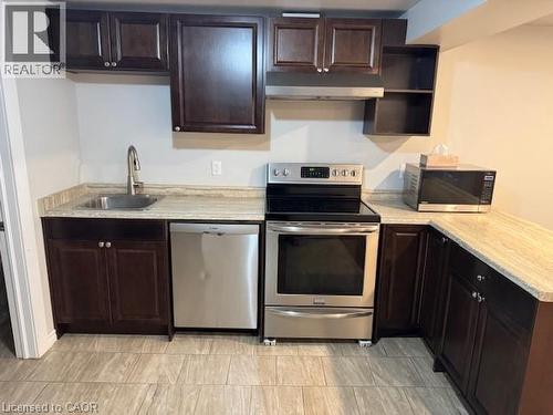 Compact kitchen featuring wood-finish cabinetry, light-toned countertops, and stainless steel appliances - 113 Cornerbrook Crescent Unit# 2, Waterloo, ON 
