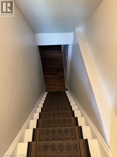 Staircase with a patterned runner and white risers, framed by light-toned walls and wood-finish flooring at the base - 113 Cornerbrook Crescent Unit# 2, Waterloo, ON 
