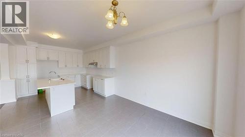 Kitchen featuring white cabinetry, a center island with an undermount sink and gooseneck faucet, light countertops, and grey tile flooring - 287 Rockledge Drive, Hamilton, ON 