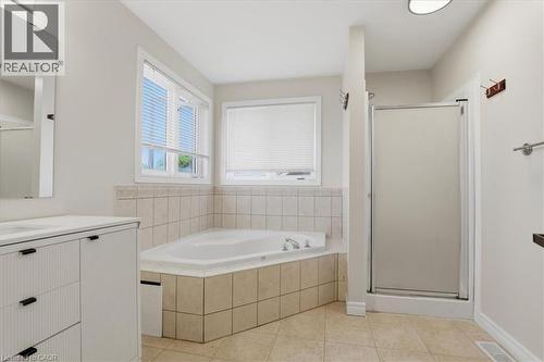 Bathroom featuring a built-in corner soaking tub with tile surround, a separate glass-enclosed shower, and a vanity with a white countertop and rectangular sink - 43 Decaro Crescent, Cambridge, ON 