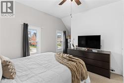 Bedroom featuring light-colored walls, multiple windows with white trim, and a ceiling fan - 