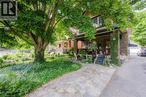 Brick facade home with a covered front porch, featuring dark trim and a red entry door - 78 Chestnut Street, Kitchener, ON 