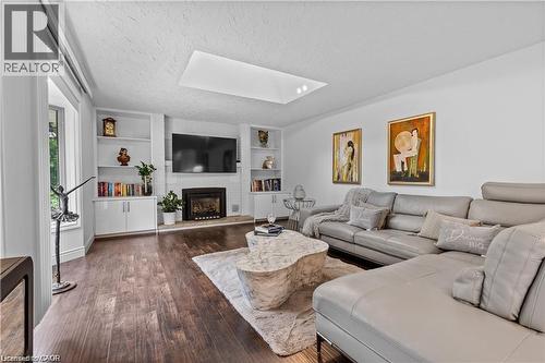 Spacious living area featuring wood-finish flooring, a contemporary fireplace with a white tile surround, and built-in shelving units - 355 Edgehill Drive, Kitchener, ON 